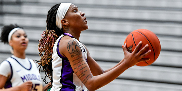 MGA women's basketball player holding basketball.